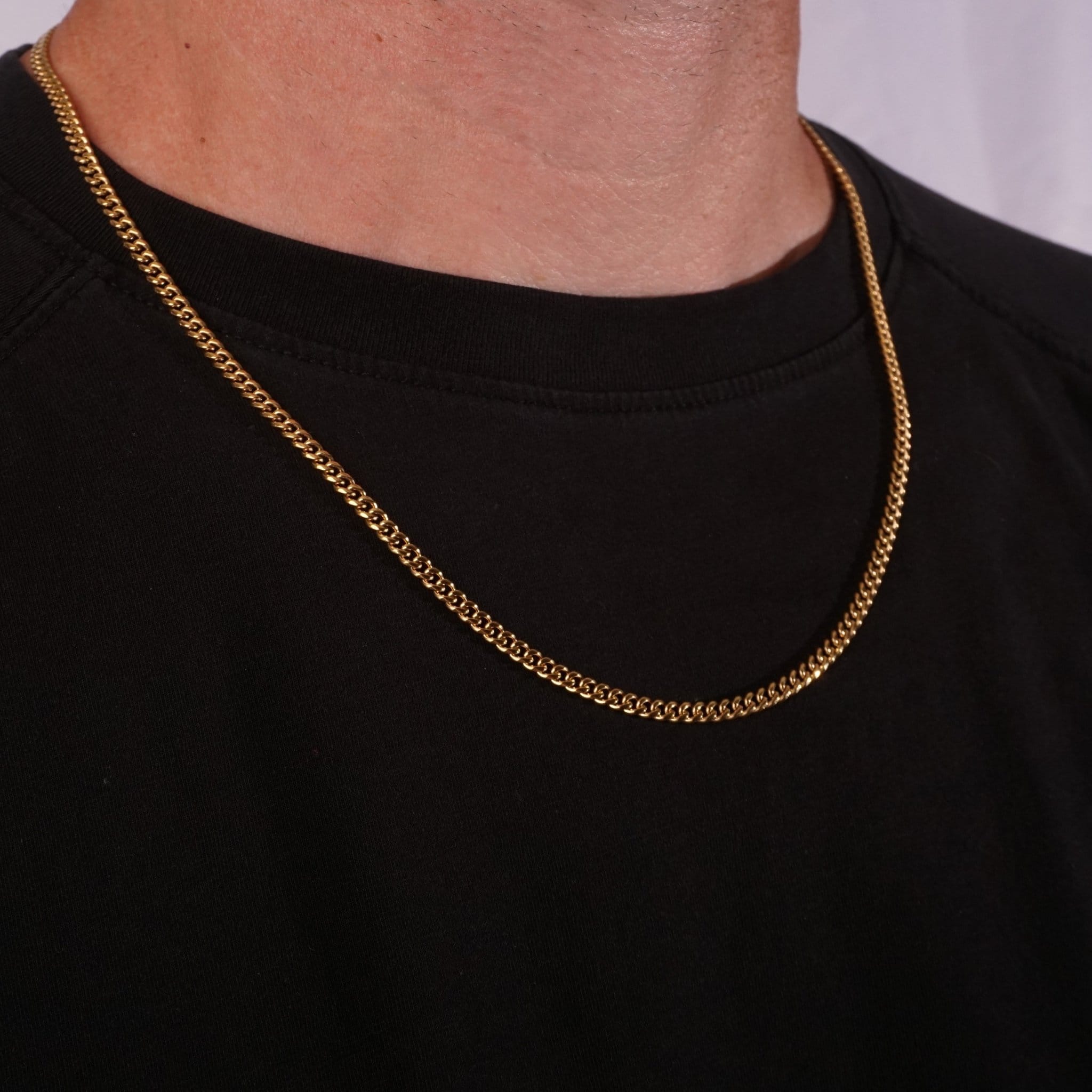 Gold cuban chain necklace on a person wearing a black shirt