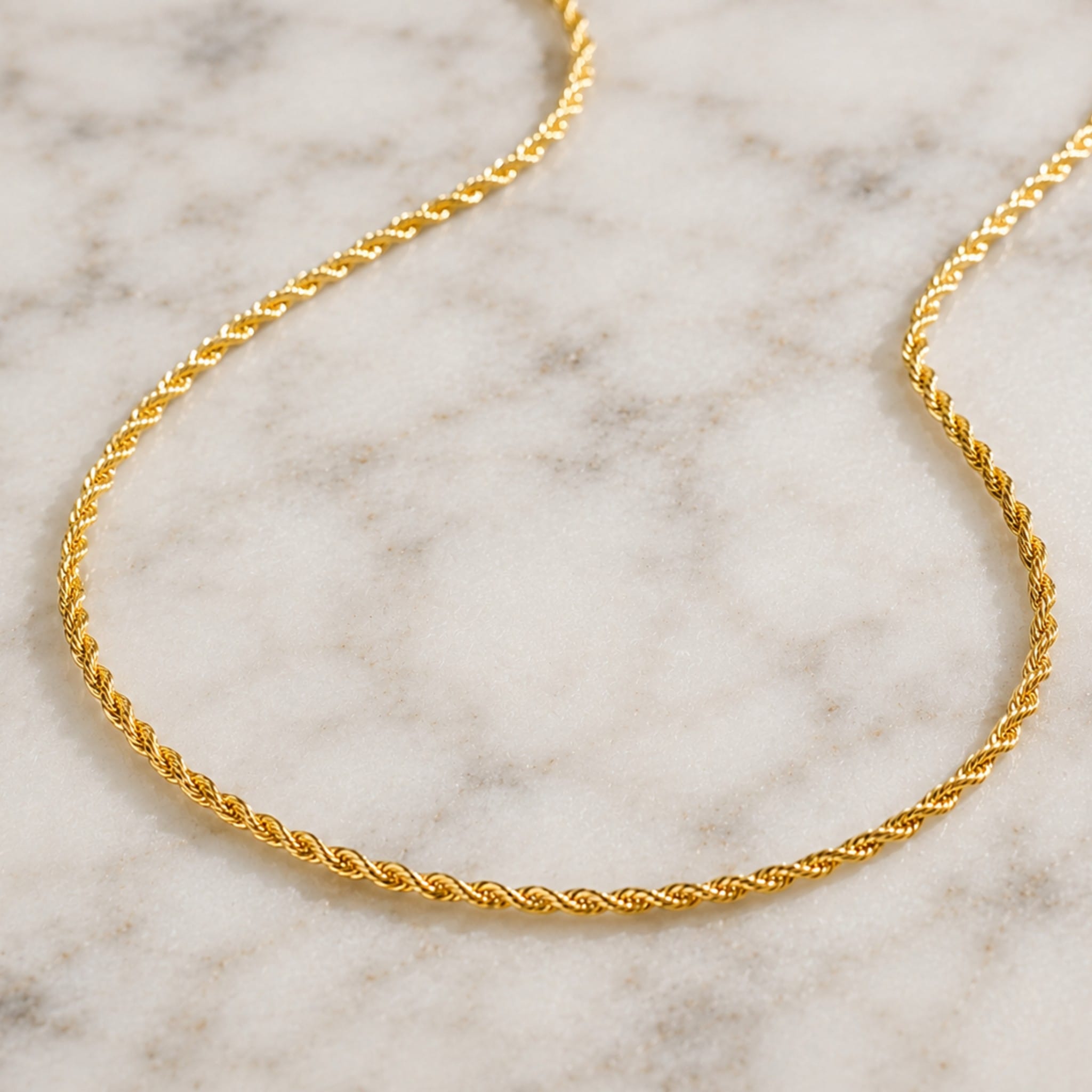 Gold rope chain necklace on a marble surface