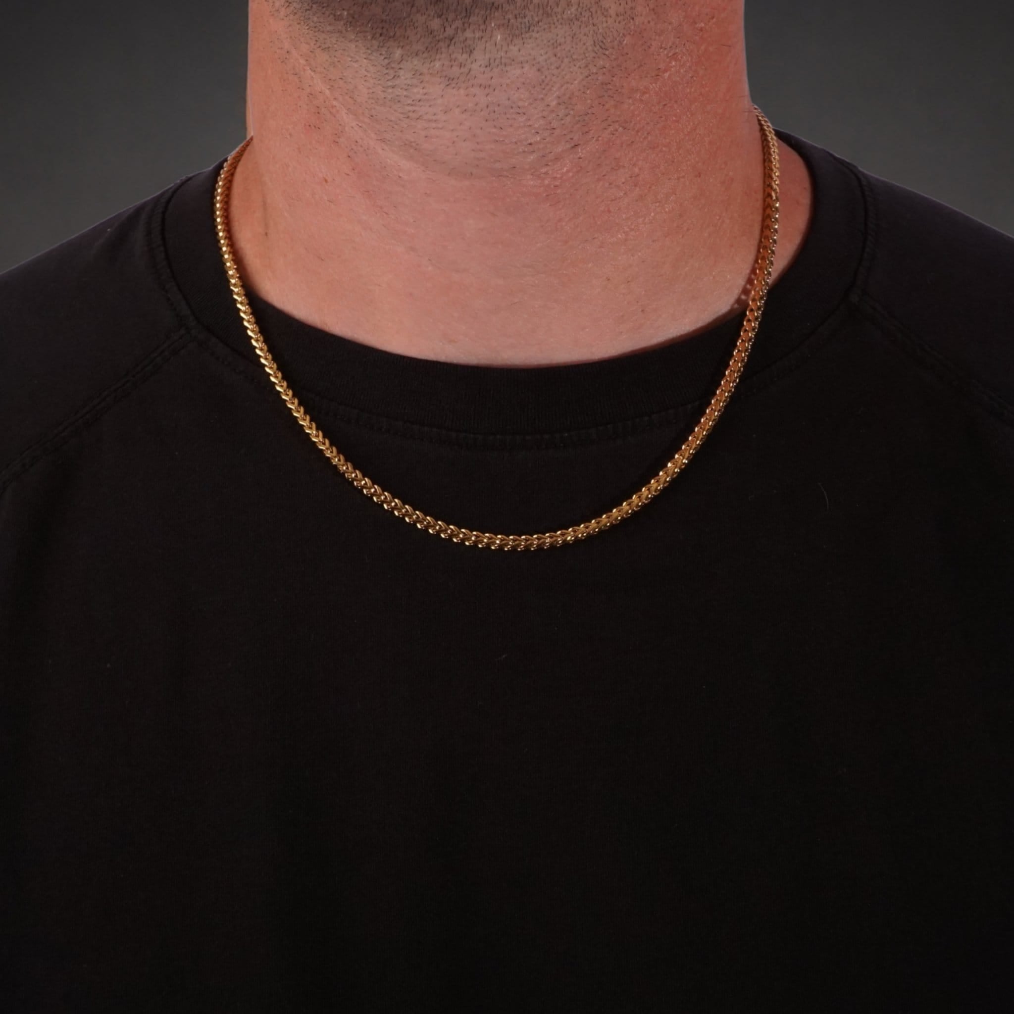 Gold franco chain necklace worn by a person on a black background