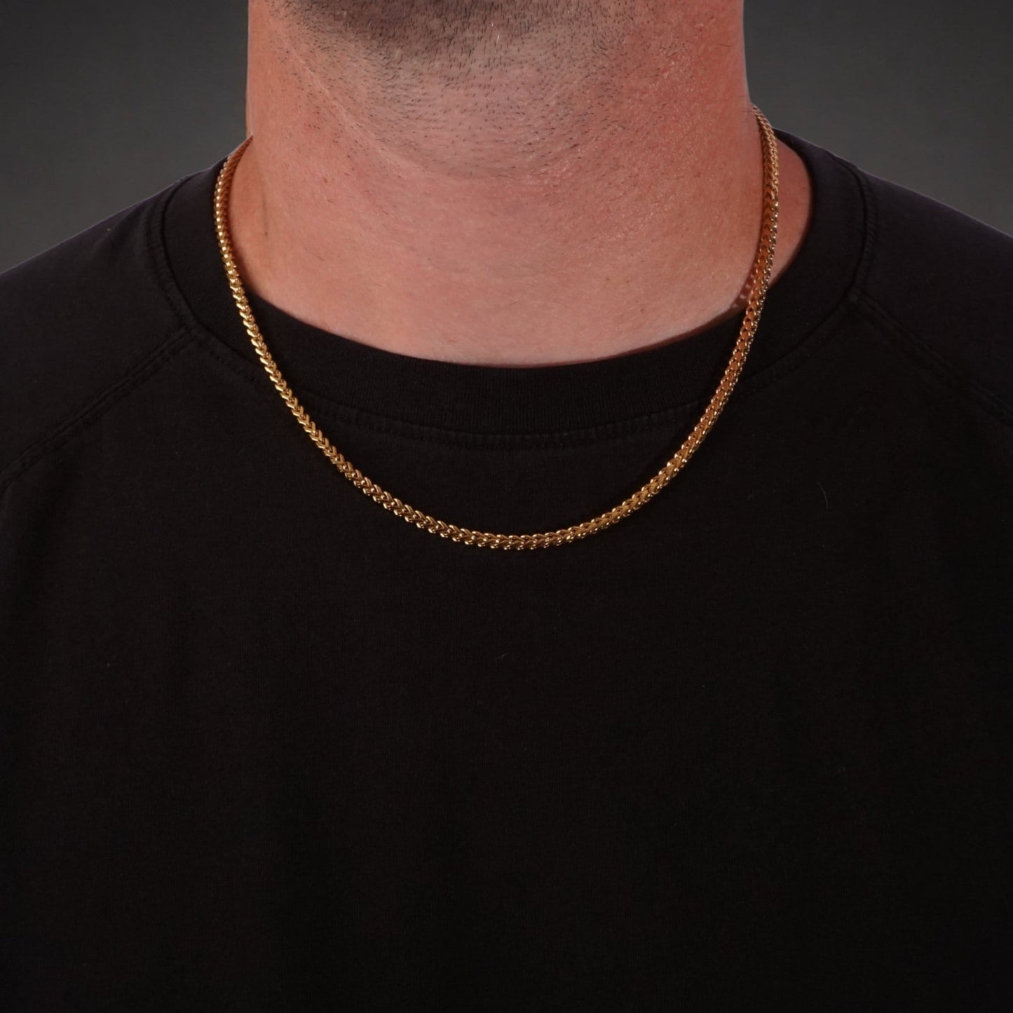 Gold franco chain necklace worn by a person on a black background