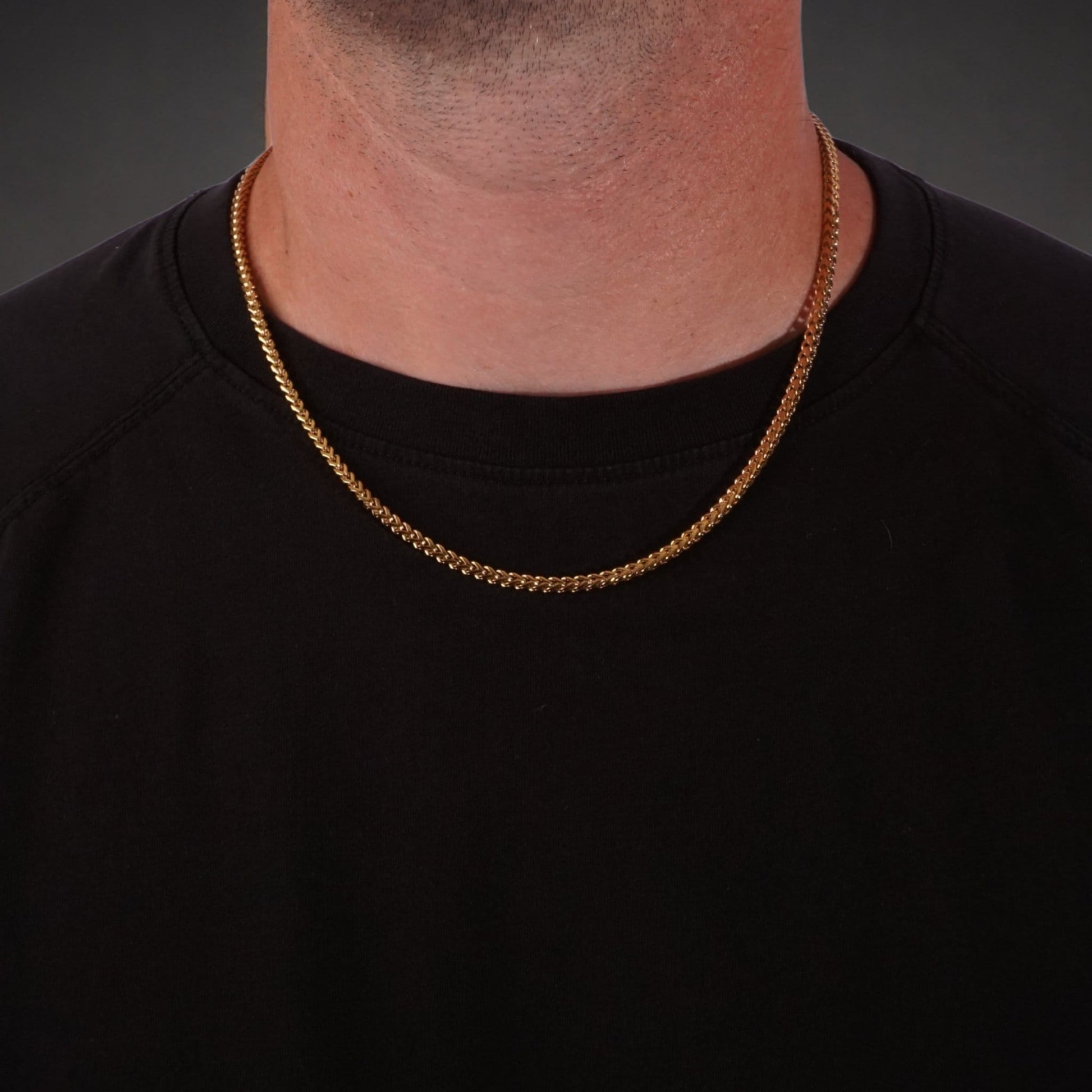 Gold franco chain necklace worn by a person on a black background