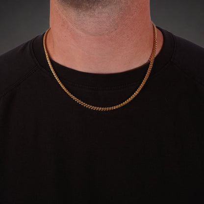 Gold franco chain necklace worn by a person on a black background