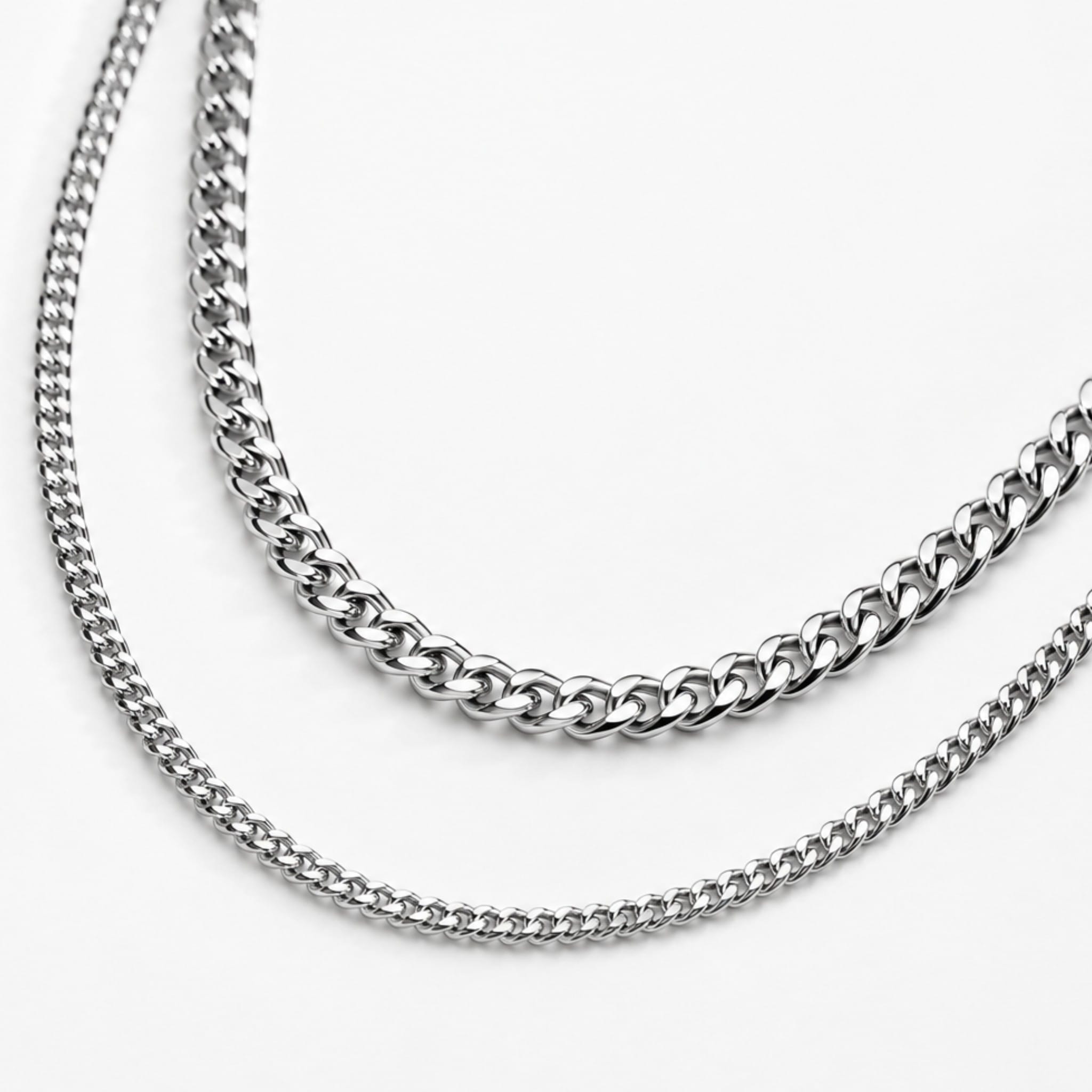Two silver cuban chain necklaces on a white background