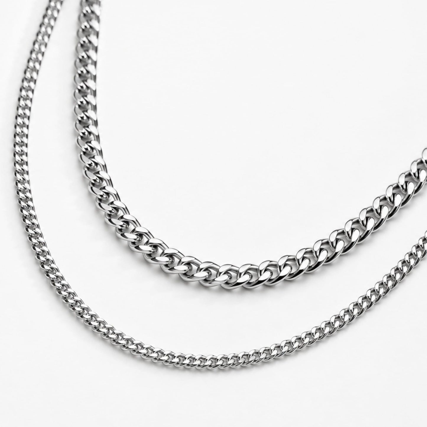 Two silver cuban chain necklaces on a white background