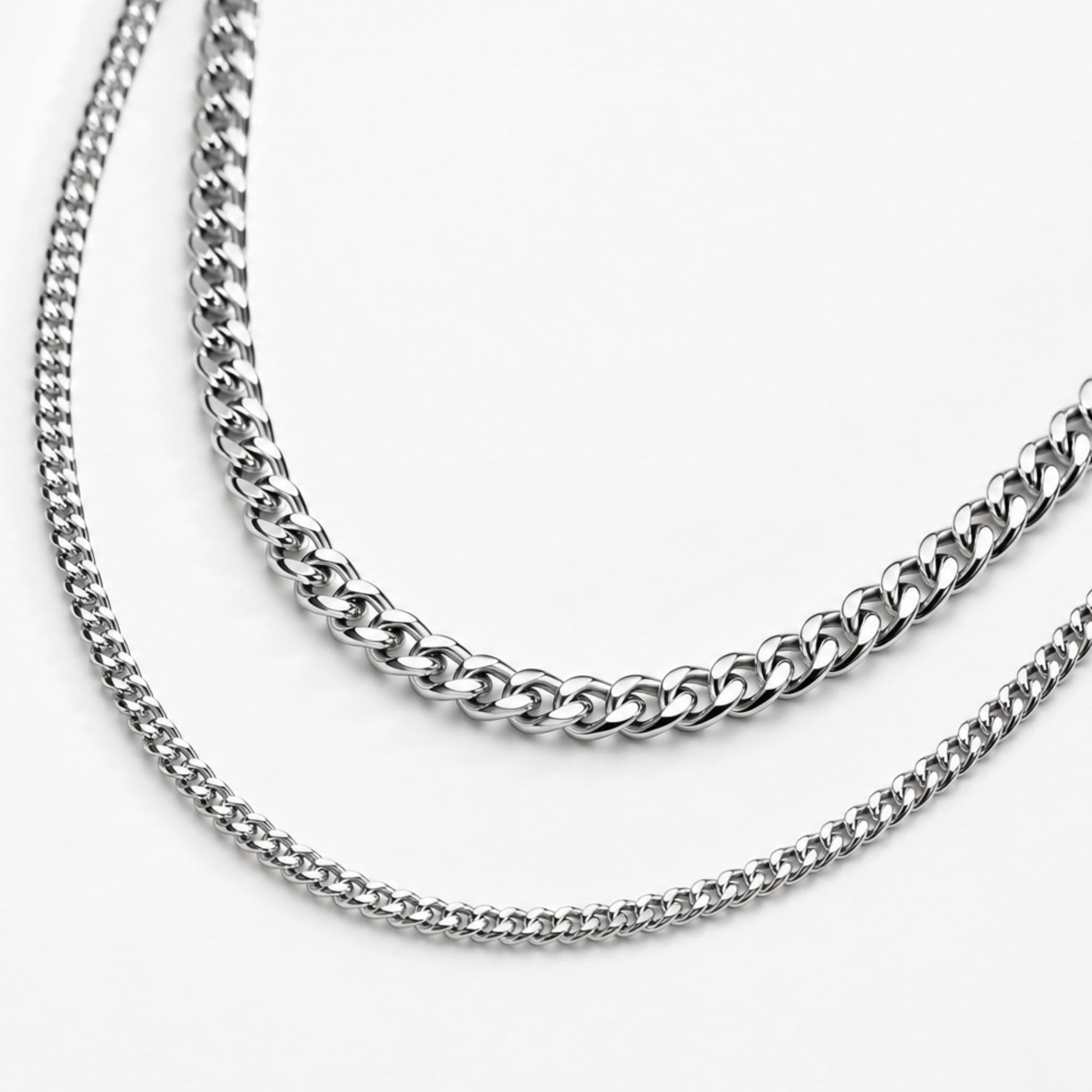 Two silver cuban chain necklaces on a white background