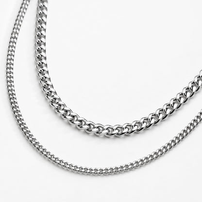 Two silver cuban chain necklaces on a white background