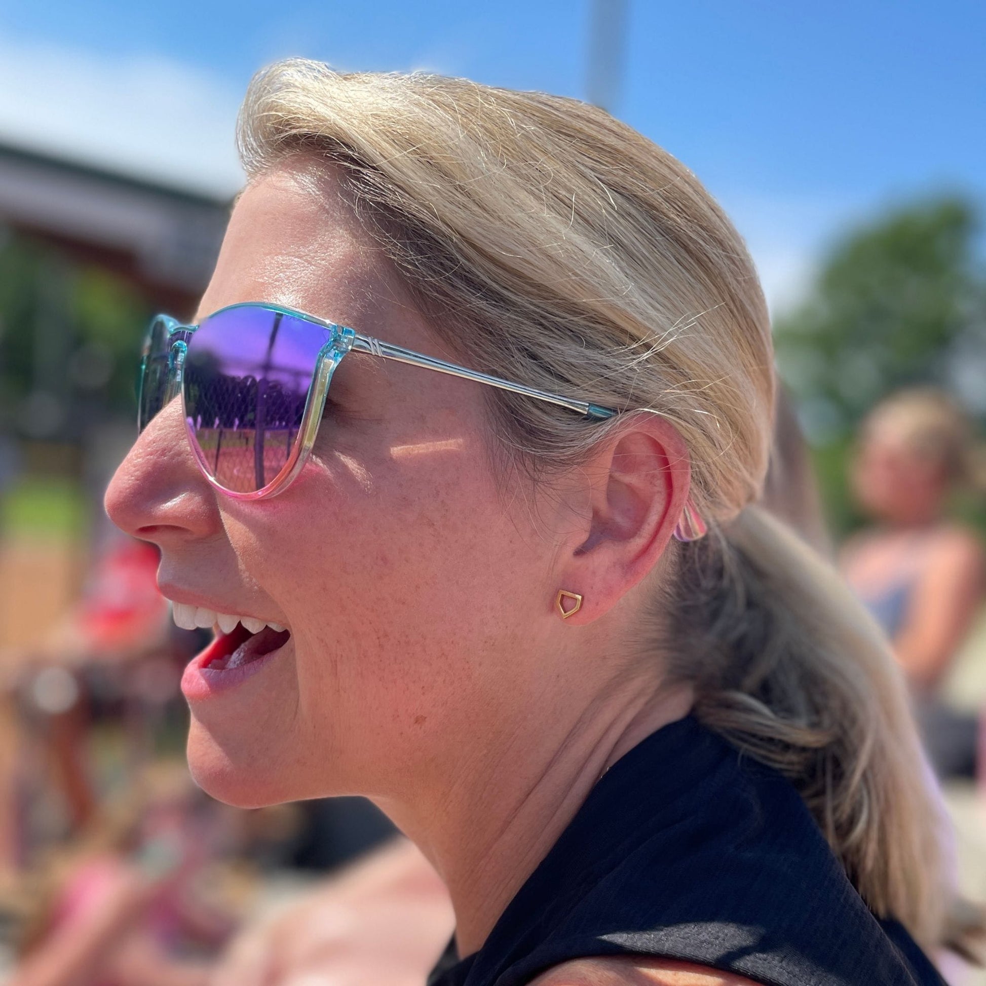 woman wearing home plate earrings and cheering in stands