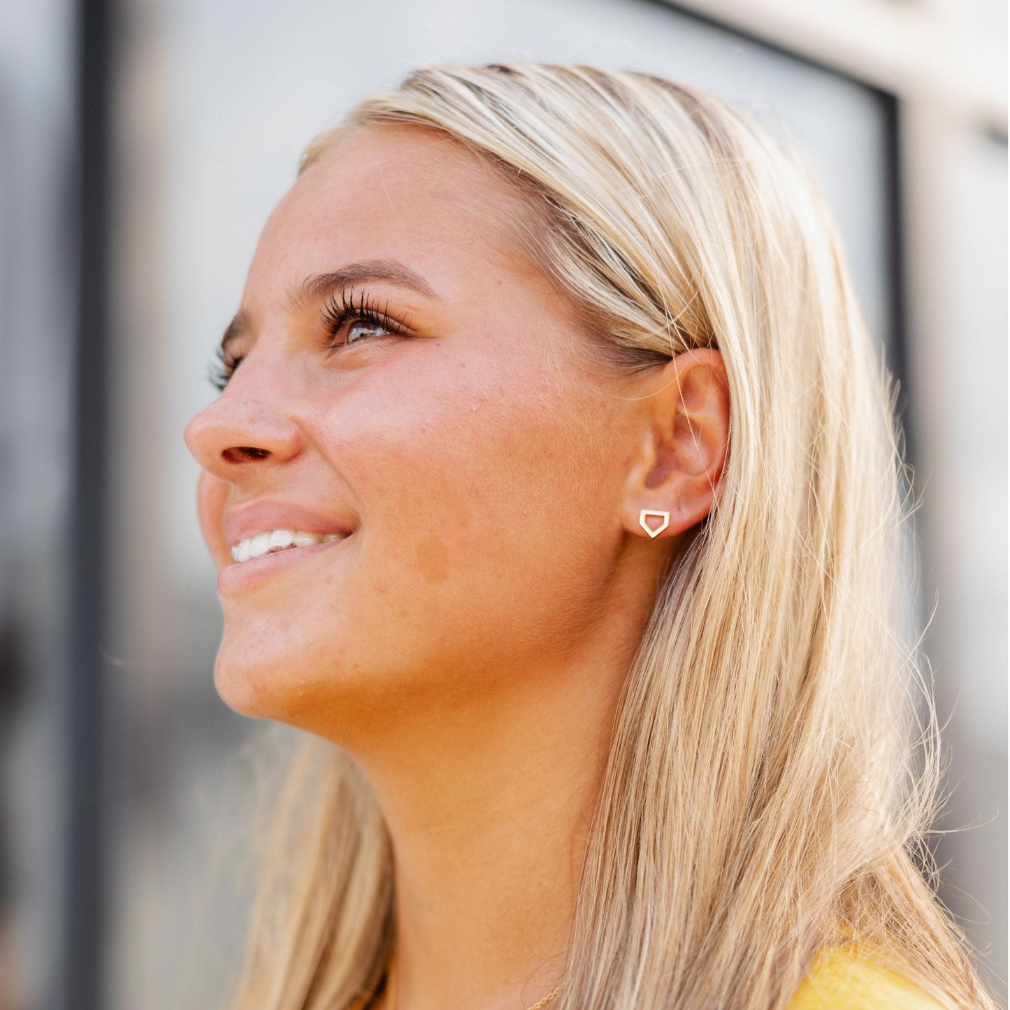 woman wearing gold home plate earrings