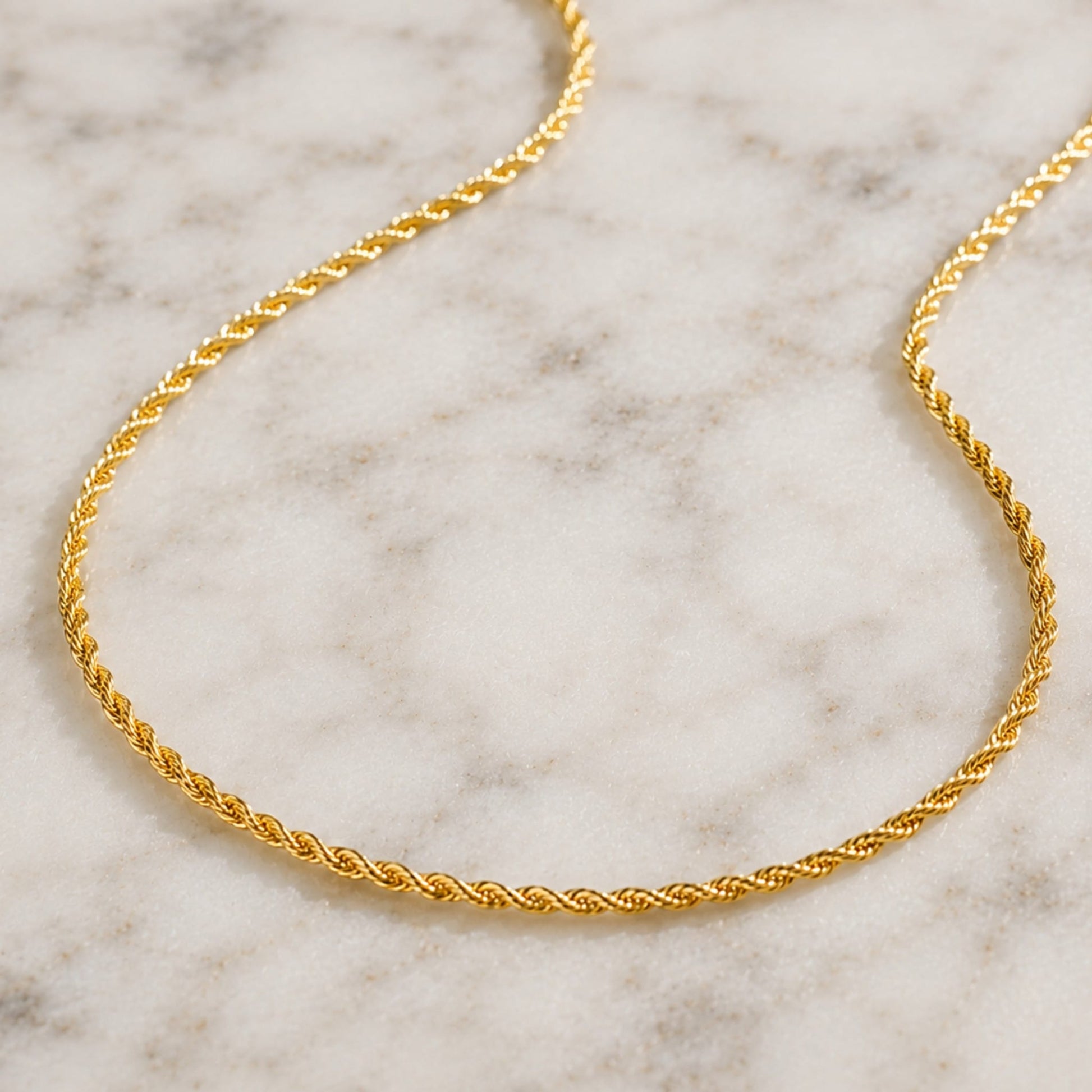 Gold rope chain necklace on a marble surface