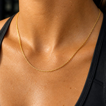 Gold rope chain necklace on a person wearing a black top
