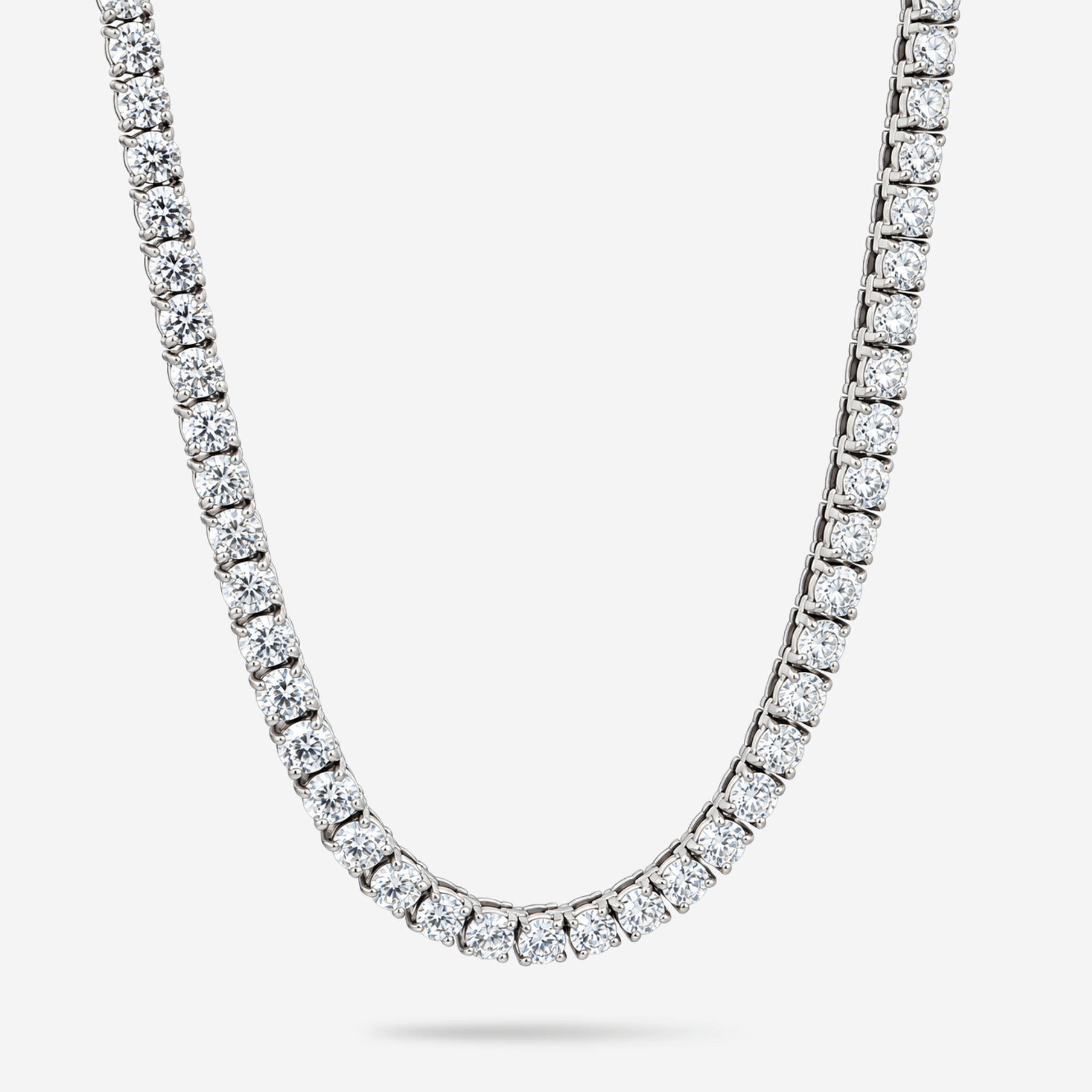A classic diamond tennis necklace in a silver-toned setting, shown curved against a light gray background.
